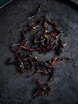 Rustic low key still life with scattered dried chillies, overhead view