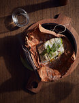 Barramundi baked in paperbark served in wooden bowl, a bush tucker dish using indigenous ingredients