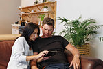 Couple reading text message on mobile phone at home