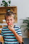 Boy biting into cupcake at home