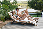 Young couple relaxing on deckchair by pond
