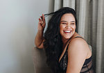 Woman in lingerie twirling hair on chair in room