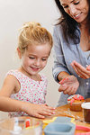 Mother and daughter decorating cupcake with frosting in kitchen