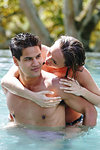 Man giving woman piggyback ride in swimming pool