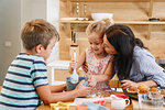 Mother and children baking cupcakes in kitchen