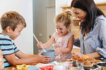 Mother and children baking cupcakes in kitchen