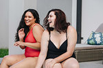 Two mid adult women sitting on outdoor pool side laughing together, Cape Town, South Africa