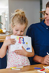 Little girl showing off drawing at home