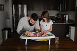 Young man and his daughter bathing baby son in kitchen