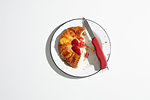 Strawberry danish pastry on plate with swiss army knife, overhead view