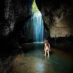 Young female tourist in bikini looking at rock formation waterfall, rear view, Bali, Indonesia