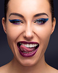 Beautiful young woman with full make up sticking out tongue