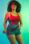 Young woman in red tank top dancing against turquoise background