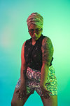 Young woman in turban dancing against turquoise background