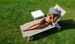 Woman relaxing with mocktail in deckchair on lawn