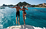 Young couple jumping into sea from yacht, La Maddalena island, Sardegna, Italy