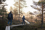 Father and son walking on planks in forest, Finland