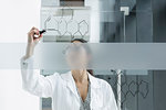 Medical student drawing atoms on glass wall in classroom