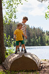 Brothers playing on upside down boat near lake, Finland