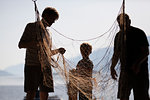 Fishermen and boy disentangling fishing net