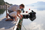 Father teaching son to tie boat to pier, Norway