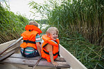 Brothers playing on boat moored in grass field