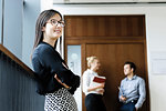 Young businesswoman in office, colleagues talking in background