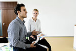 Businessman with VR headset and businesswoman talking in office