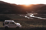 Off road vehicle in desert, sunset over mountain ranges, Landmannalaugar, Highlands, Iceland