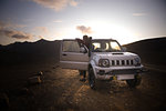 Woman traveller enjoying scenic view beside vehicle, Landmannalaugar, Highlands, Iceland