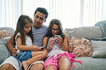 Father watching daughters play computer games on cellphone