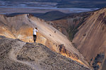 Woman photographing from ridge of hill, Landmannalaugar, Iceland