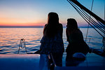 Friends watching sunset on sailboat, Italy