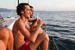 Young men enjoying champagne on sailboat, Italy