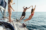 Friends jumping off sailboat into sea, Italy