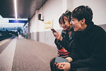 Young couple sharing text on train platform, Milan, Italy