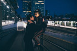 Young couple laughing and hugging in train station, Milan, Italy