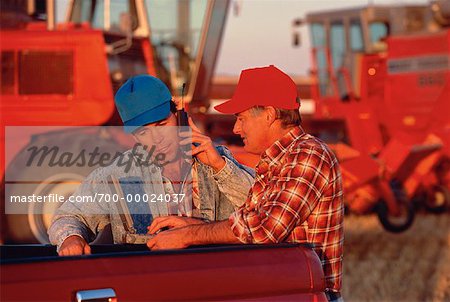 Farmers Using Cell Phone and Laptop Computer at Sunset St. Agathe, Manitoba, Canada