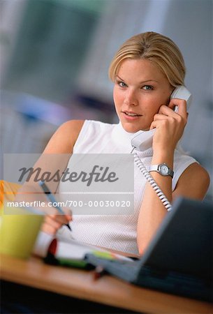 Portrait of Businesswoman Sitting At Desk, Using Phone