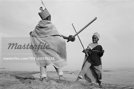 Boys Play Fighting on Beach Dressed as Knights