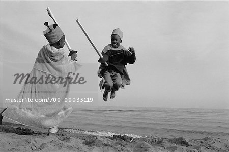 Jungen spielen am Strand, die verkleidet als Ritter kämpfen