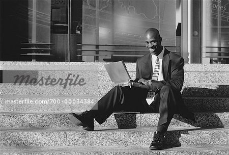 Homme d'affaires assis sur les marches à l'aide d'ordinateur portable