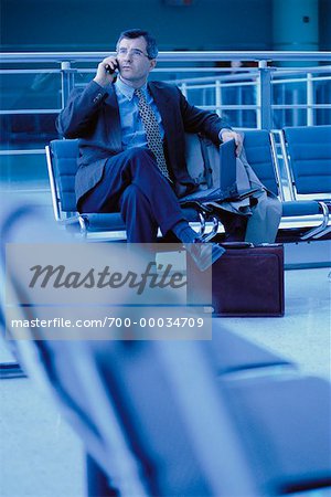 Businessman Using Cell Phone and Laptop Computer at Airport