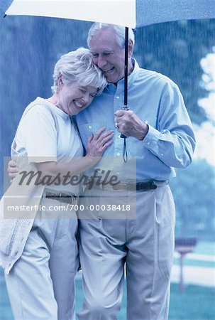 Mature Couple Walking Under Umbrella in Rain