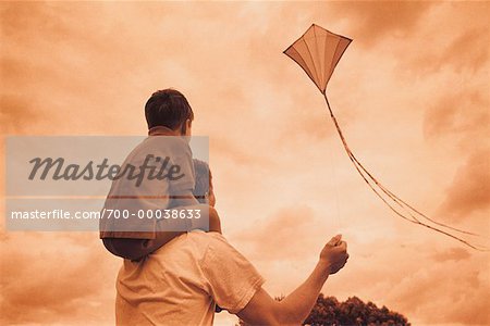 Back View of Father and Son Flying Kite