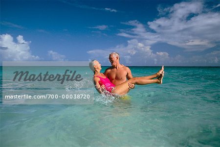 Mature Couple en maillot de bain, homme portait la femme dans l'eau