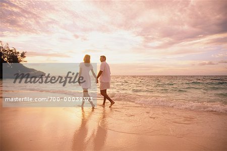 Couple marchant sur la plage, main dans la main