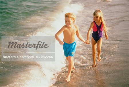 Boy und Girl in Bademode, Wandern am Strand, die Hand in Hand