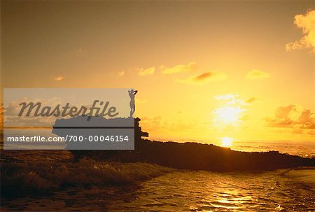 Silhouette der Frau stehen auf Felsen im Wasser bei Sonnenuntergang
