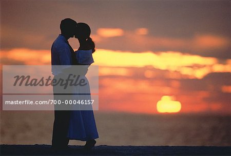 Couple embrassant sur la plage au coucher du soleil